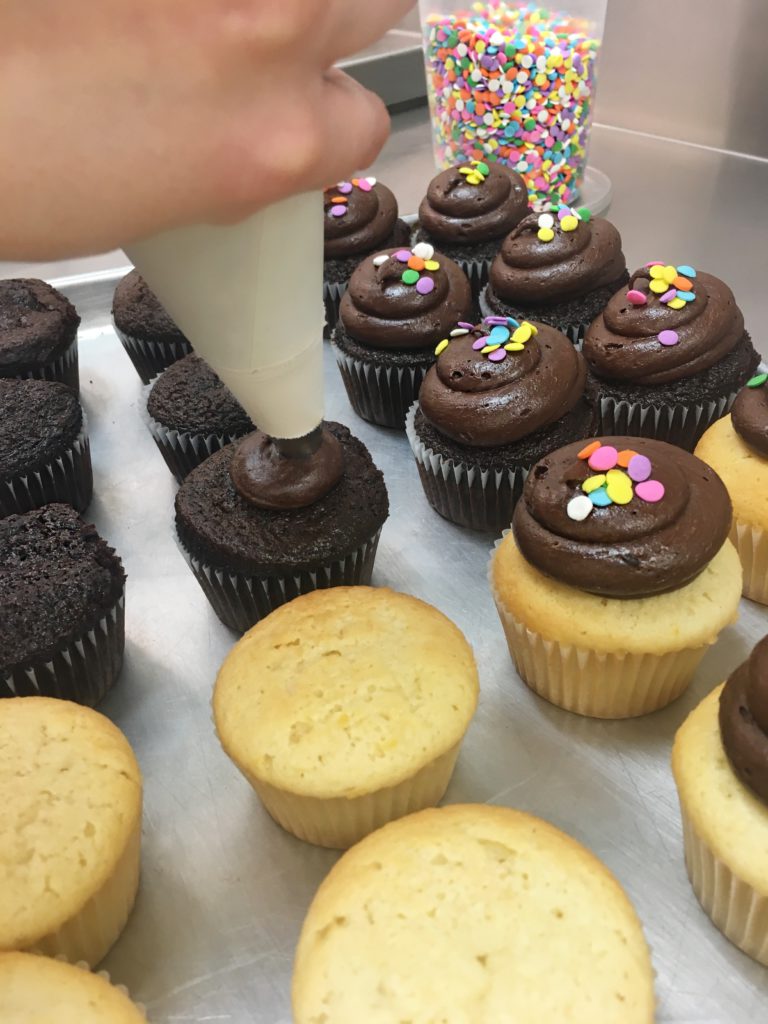 Adding icing to cupcake gifts in Toronto